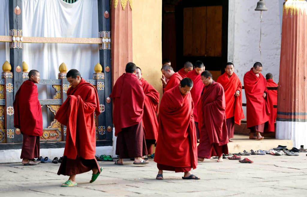 Buddhist monks in red robes gather at Trongsa Monastery, Bhutan, showcasing traditional culture.